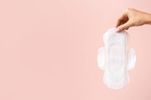 Female hand with menstrual pad on color background - Fotografie, Obrázek