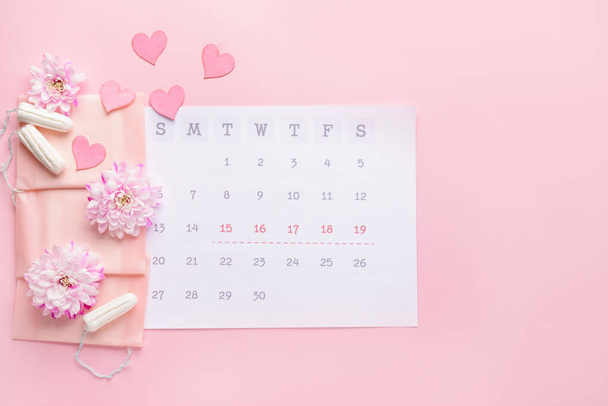 Calendario menstrual con productos femeninos sobre fondo de color
 - Foto, imagen