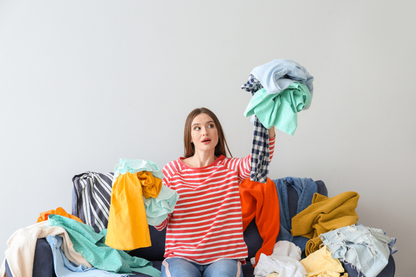 Проблемная женщина с кучей одежды на диване в помещении
 - Фото, изображение