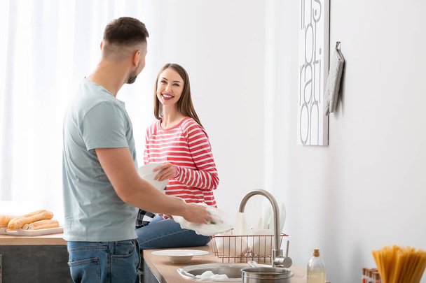 Happy couple washing dishes in kitchen - Photo, Image