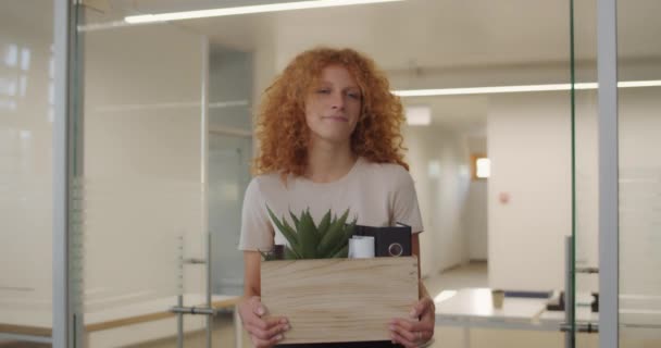 Young dismissed woman walking sadly and holding box with her belongings. Fired young female worker leaving office with box and multiethnic colleagues symphathizing her. Concept of work. - Footage, Video