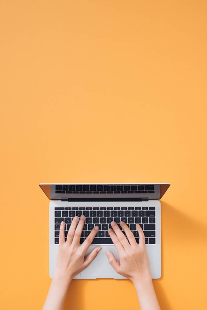 Colocação plana de laptop, café e notebook sobre fundo amarelo. Mãos femininas digitando no teclado
 - Foto, Imagem