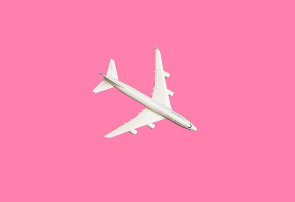 Μοντέλο αεροπλάνο, αεροπλάνο σε ροζ παστέλ χρώμα φόντο με χώρο αντιγραφής. Επίπεδη σχεδίαση. Ταξίδια έννοια σε ροζ φόντο. ανώτερο επίπεδο μοντέλου προβολής σε ροζ χρώμα φόντου. - Φωτογραφία, εικόνα