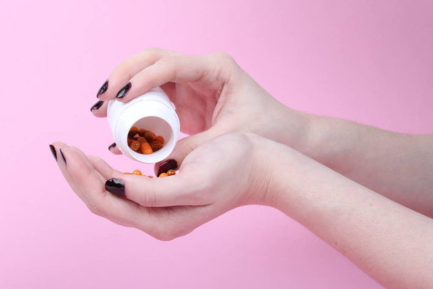 prescription drugs spilled into the hands of a woman on a pink background - Foto, afbeelding