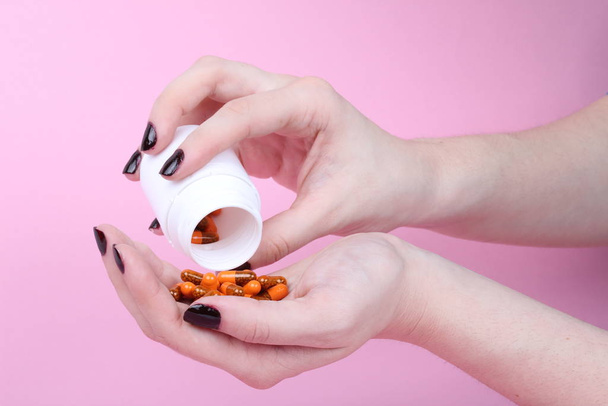 medicamentos prescritos derramados nas mãos de uma mulher em um fundo rosa
 - Foto, Imagem