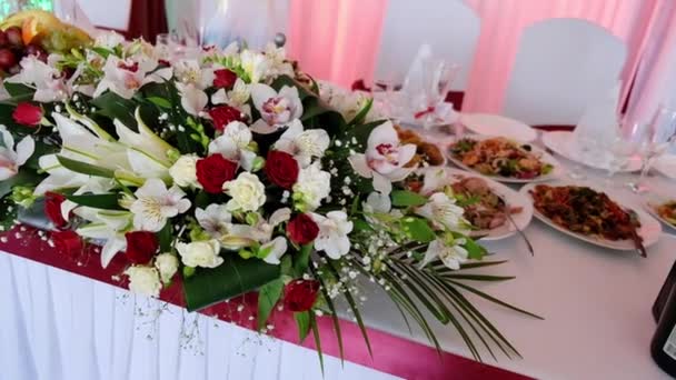 Svatební zdobený sál s flórou. Nastavení stolu s čerstvými květinami. Banketový sál - Záběry, video