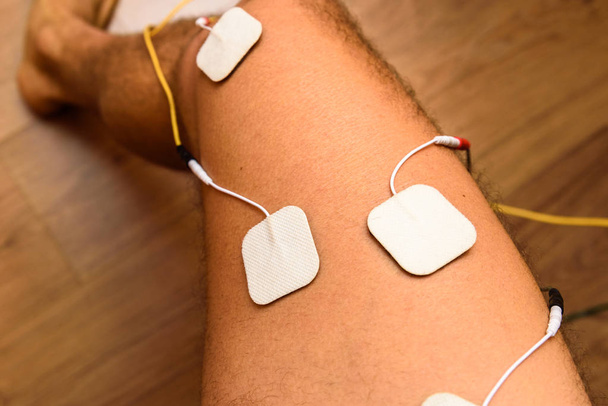 Un atleta lesionado aplica electrodos ems a sus piernas para recuperarse
 - Foto, imagen