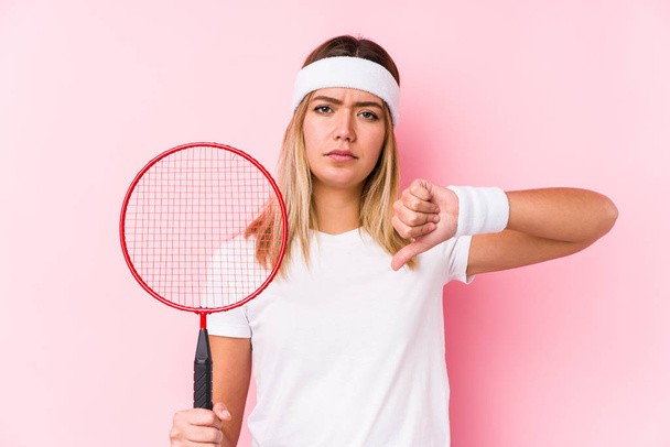 junge Frau, die isoliert Badminton spielt und eine ablehnende Geste zeigt, Daumen nach unten. Unstimmigkeiten. - Foto, Bild