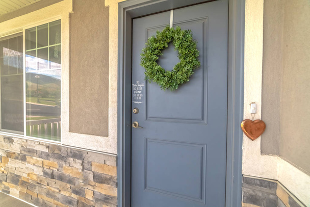 Home exetrior com close-up na porta da frente cinza azul decorado com grinalda verde
 - Foto, Imagem
