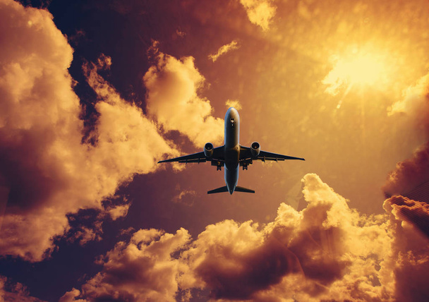 Vliegtuig vliegen boven dramatische wolken tijdens zonsondergang, zonsopgang. - Foto, afbeelding