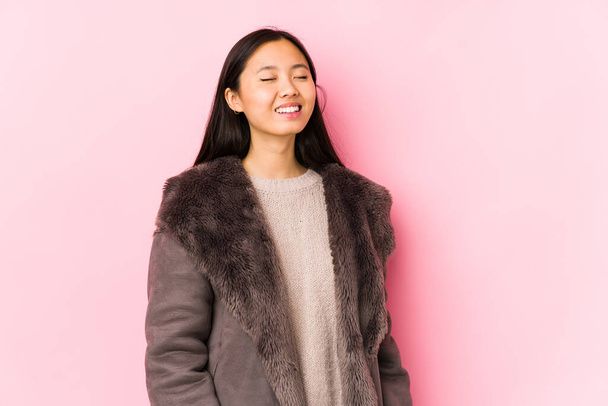 Young chinese woman wearing a coat isolated relaxed and happy laughing, neck stretched showing teeth. - Photo, Image
