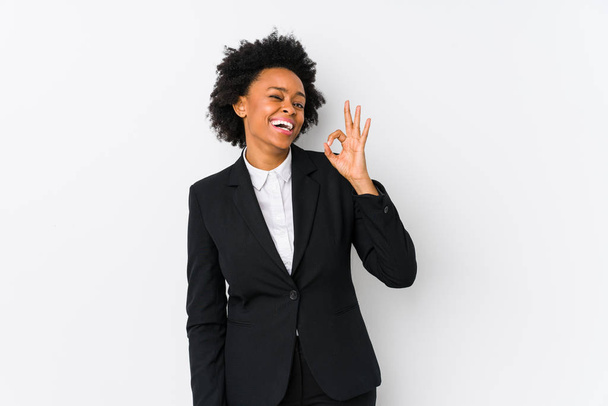 中年アフリカ系アメリカ人ビジネス女性に対して白の背景孤立ウィンク目と手で正しいジェスチャーを保持. - 写真・画像