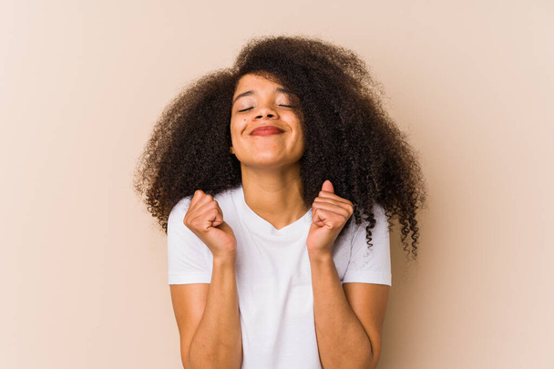 Fiatal afro-amerikai nő felemeli az öklét, boldognak és sikeresnek érzi magát. Győzelmi koncepció. - Fotó, kép