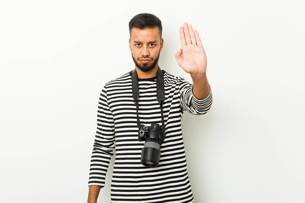 Молодий південноазіатський фотограф стоїть з простягнутою рукою, показуючи знак зупинки, запобігаючи вам
. - Фото, зображення