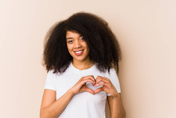 Young african american woman smiling and showing a heart shape with hands. - Фото, изображение