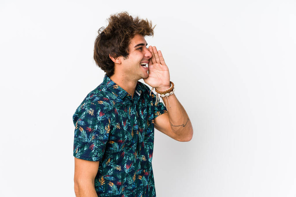 Молодой кавказский мужчина в цветочной футболке, кричащий и держащий ладонь у открытого рта
. - Фото, изображение