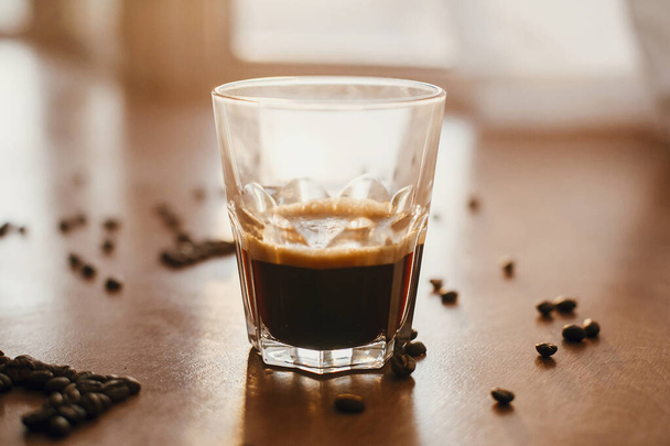 Ζεστός espresso με αφρό σε γυάλινο κύπελλο με αρωματικό φρυγμένο καφέ - Φωτογραφία, εικόνα