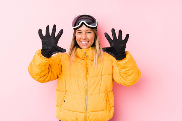 Young caucasian woman wearing a ski clothes in a pink background showing number ten with hands. - Photo, Image