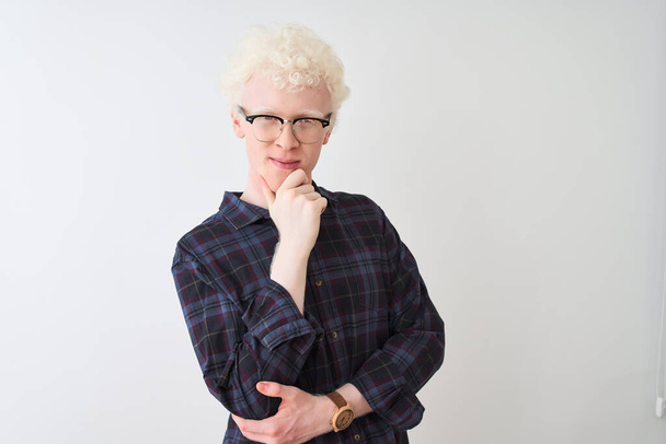Jeune homme blond albinos portant chemise décontractée et lunettes sur fond blanc isolé regardant avec confiance la caméra souriant avec les bras croisés et la main levée sur le menton. Penser positif
. - Photo, image