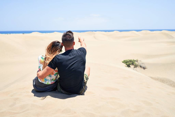 Young beautiful couple  at sitting backwards and hugging at the beach - Foto, imagen