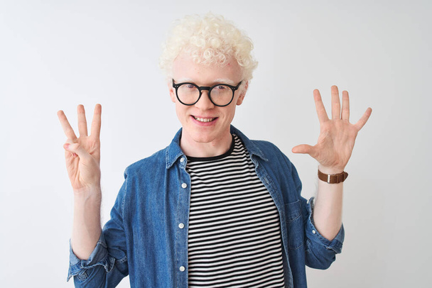 Jonge albino blonde man draagt denim shirt en bril over geïsoleerde witte achtergrond tonen en wijzen met vingers nummer acht, terwijl glimlachen zelfverzekerd en gelukkig. - Foto, afbeelding