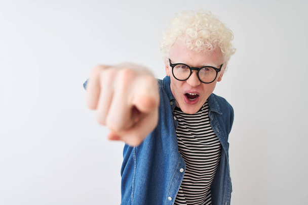 Jeune homme blond albinos portant chemise en denim et lunettes sur fond blanc isolé pointant mécontent et frustré à la caméra, en colère et furieux contre vous
 - Photo, image