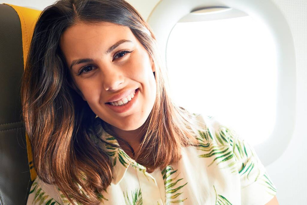 Giovane viaggiatore donna seduta dentro aereo all'aeroporto con vista cielo dalla finestra
 - Foto, immagini