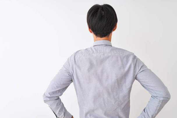 Chinese zakenman draagt elegante stropdas staan over geïsoleerde witte achtergrond staan achteruit kijken weg met armen op het lichaam - Foto, afbeelding