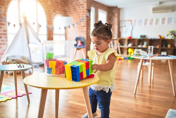 美しい幼児は幼稚園でブロックおもちゃを作ってテーブルで遊んでいます - 写真・画像