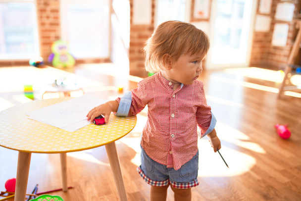 Adorable niño jugando alrededor de un montón de juguetes en el jardín de infantes
 - Foto, Imagen