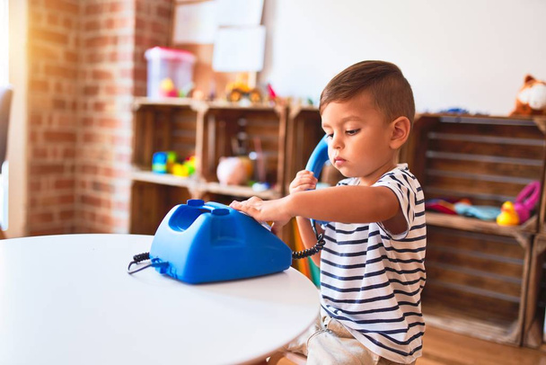Menino da criança bonita brincando com o telefone azul vintage no jardim de infância
 - Foto, Imagem