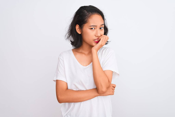 Jeune femme chinoise portant t-shirt décontracté debout sur fond blanc isolé regardant stressé et nerveux avec les mains sur les ongles mordants de la bouche. Problème d'anxiété
. - Photo, image