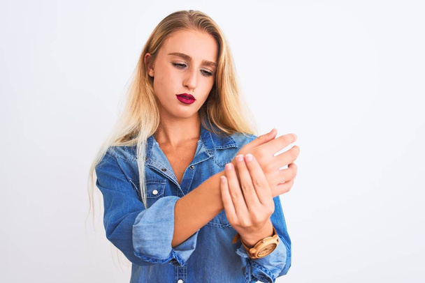 Young beautiful woman wearing casual denim shirt standing over isolated white background Suffering pain on hands and fingers, arthritis inflammation - Photo, Image