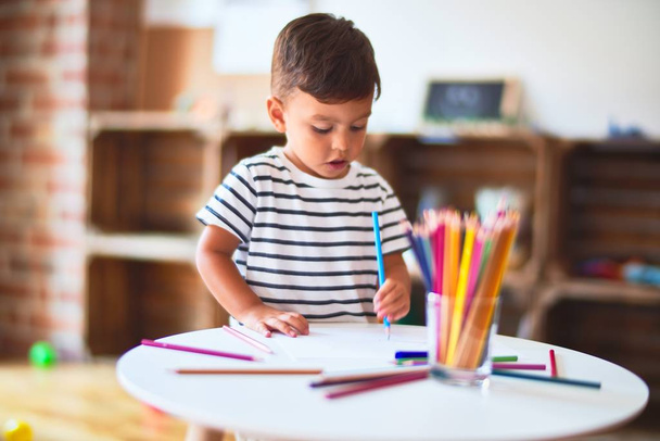 美しい幼児の男の子は幼稚園で色鉛筆を使ってかわいい絵を描く - 写真・画像