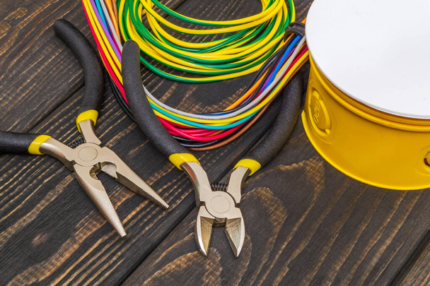 Caixa de junção elétrica amarela com fios de cabos e ferramentas usadas no processo de instalação elétrica
 - Foto, Imagem