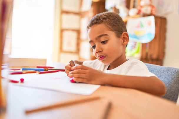 Gyönyörű afro-amerikai kisgyermek ül festészet autós játék segítségével marker toll íróasztal óvoda - Fotó, kép