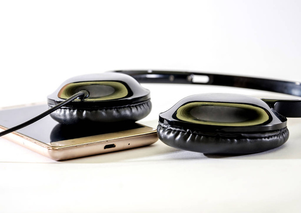 auriculares negros y smartphone sobre fondo blanco. Primer plano
. - Foto, Imagen