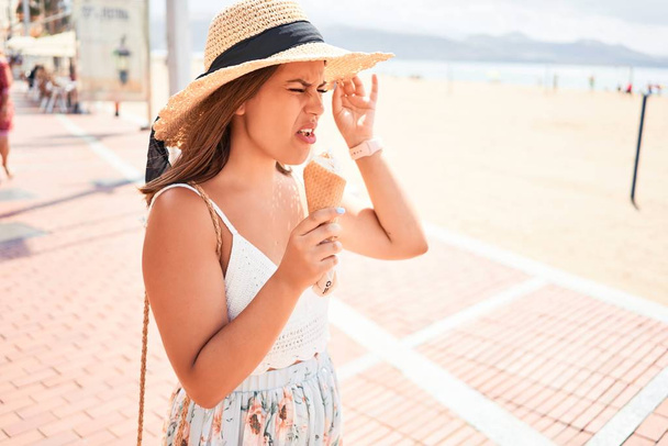Giovane bella donna mangiare cono gelato in spiaggia in una giornata di sole d'estate in vacanza
 - Foto, immagini