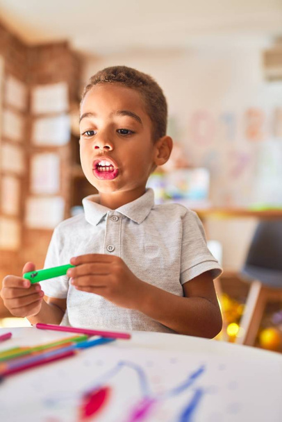 Hermoso dibujo de niño afroamericano utilizando papel y rotulador en el jardín de infantes
 - Foto, Imagen