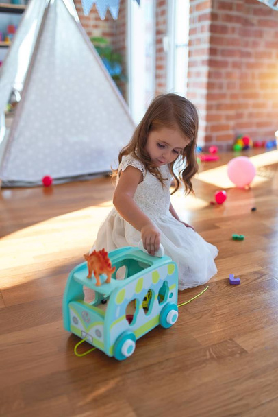 entzückendes blondes Kleinkind spielt im Kindergarten mit Auto-Spielzeug um jede Menge Spielzeug - Foto, Bild