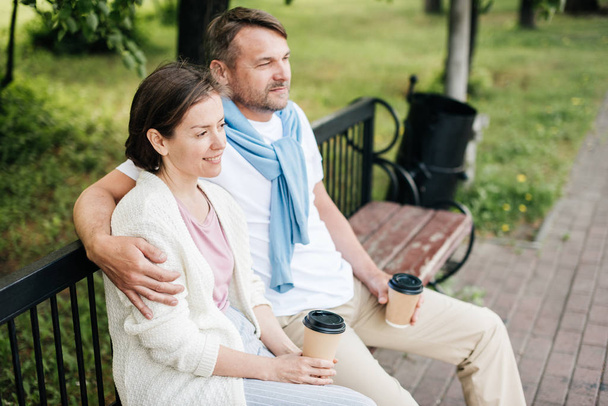Married couple sit on the bench hugging in the park. - Foto, Bild