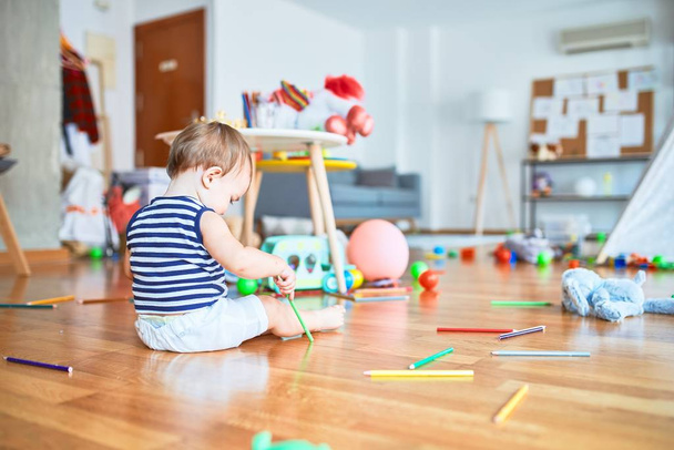 Adorable niño jugando alrededor de un montón de juguetes en el jardín de infantes
 - Foto, imagen