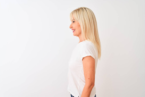 Kobieta w średnim wieku ubrana w luźny t-shirt stojący nad odizolowanym białym tłem patrząc na bok, relaks poza profilem z naturalną twarzą i pewny uśmiech. - Zdjęcie, obraz