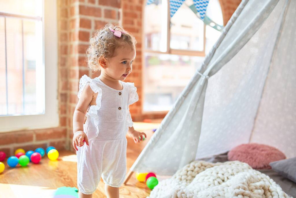 Beau bébé caucasien jouant avec des jouets à la salle de jeux colorée. Heureux et ludique avec tente indienne à la maternelle
. - Photo, image