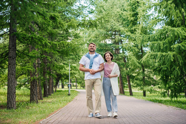 Married couple walking in the park in summer. - Zdjęcie, obraz