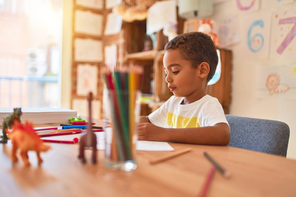 Bella africano americano bambino seduto pittura auto giocattolo utilizzando pennarello sulla scrivania alla scuola materna
 - Foto, immagini