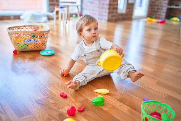 Adorable blonde toddler playing around lots of toys at kindergarten - Φωτογραφία, εικόνα