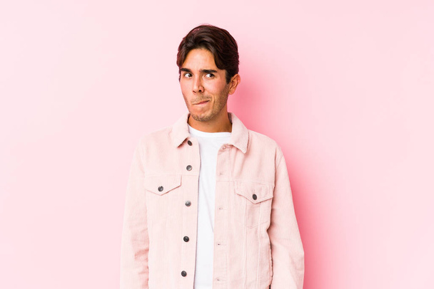 Young caucasian man posing in a pink background isolated confused, feels doubtful and unsure. - Photo, Image