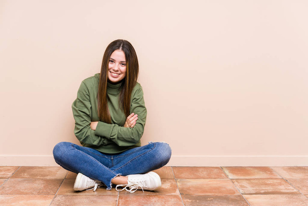 Young caucasian woman sitting on the floor isolated laughing and having fun. - Fotografie, Obrázek