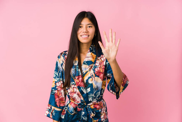 Giovane donna asiatica indossa un pigiama kimono sorridente allegro mostrando il numero cinque con le dita
. - Foto, immagini